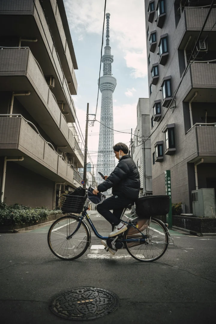 Un homme à vélo regarde son téléphone devant la Tokyo Skytree