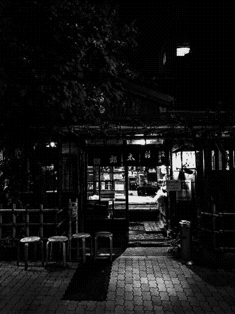 Entrance of a traditional Japanese restaurant at night, with wooden stools